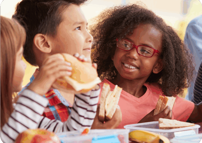 young children smiling and eating lunch at school